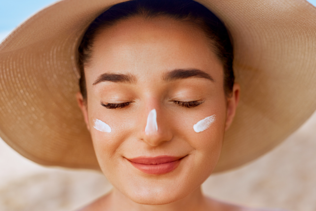A woman at the beach with sunscreen on her face symbolizing the importance of daily sunscreen use.